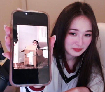 tinakitten holding up her phone with a picture of foolish_gamers inside a box